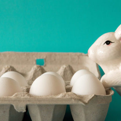 bunny statue watches eggs Ceramic bunny with eggs on turquoise background.