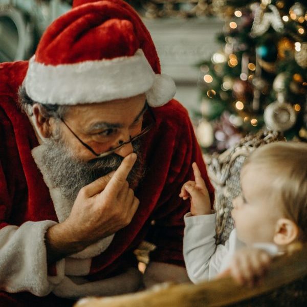 Santa Claus interacting with a curious child.