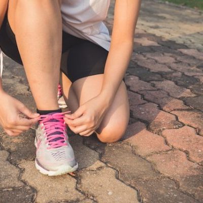 Person tying running shoe on pavement.